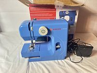 Singer M1000 sewing machine front view with foot pedal and box