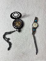Pocket watch open showing skeleton movement and chain; wristwatch displayed beside
