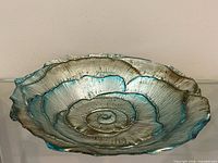Angled view showing metallic silver glass bowl with teal highlights and fluted rim
