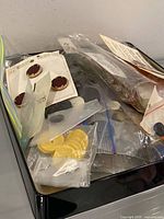 Tray filled with zip bags and cards of assorted buttons; Woolco Values burgundy buttons visible