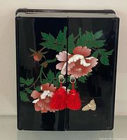 Front view of black lacquer jewelry box with floral design and tassels