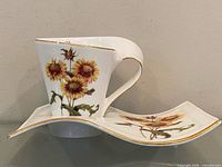 Teacup resting on saucer, side profile shows wavy shape and decoration