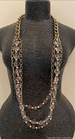 Full view of necklace on display bust showing bead strands and chain