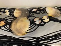 close-up of central large abalone shell disc and cord connections