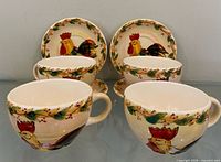 Set of four cups in front with four saucers behind, showing rooster motif