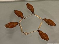 Overall view of bracelet in hexagonal layout showing six carved olive pit beads and gold-tone links