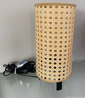 Front view of IKEA Saxhyttan table lamp, showing rattan shade and power cord