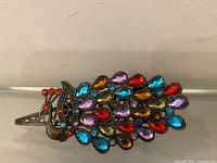 Top view of full peacock hair clip showing multicolour rhinestones and metal clip