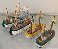 Four miniature wooden fishing boats in various hull colors displayed together