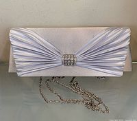 Front view of silver satin pleated clutch with chain strap displayed