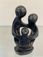 Front view of black stone family sculpture on base