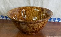Side profile of brown mottled earthenware bowl on wood surface