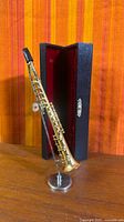 full view of sax on stand beside open case