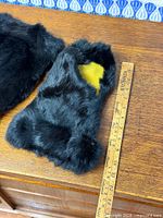 Top view of left mitten showing black mink fur and yellow leather lining with ruler for scale