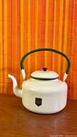 Full view of white enamel kettle with green handle and H&H logo