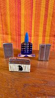 Front view of four vintage lighters on wooden surface