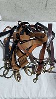 Pile of seven assorted leather bag straps showing colours and hardware