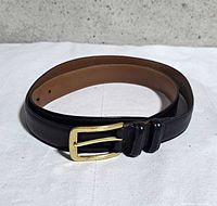 Full view of coiled black leather belt showing outer color and tan lining
