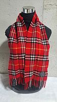 Full view of scarf draped on mannequin showing plaid pattern and fringe