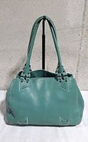 Front view of Cole Haan turquoise leather handbag on stand