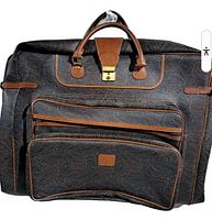 Front view of Etro coated canvas garment bag showing paisley pattern, two exterior zip compartments, leather handles and brass lock