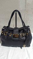 Front view of black leather Jimmy Choo Ross satchel showing gold hardware and push-lock clasp