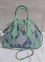 Front view showing argyle canvas, leather trim, orb logo, handles, strap