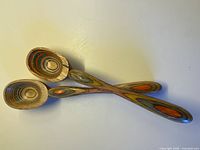 Two laminated dyed wood spoons crossed on surface