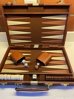 Open backgammon case showing board layout, dice cups, checkers, dice, doubling cube, handle and latches