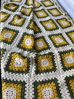 Full view of folded crocheted blanket showing square pattern and colors