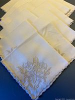 Stack of linen napkins showing embroidery and scalloped edges