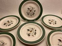 Six dessert plates arranged showing green rim and apple blossom design