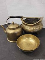 Group shot of brass kettle, engraved tripod bowl, and plain bowl