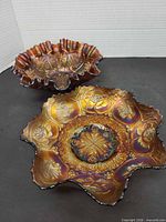 Two iridescent carnival glass bowls showing pattern and ruffled edges