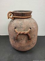 front view of rustic earthenware pot showing rope handles