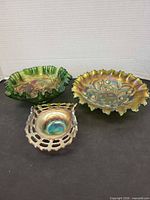Three carnival glass pieces: two ruffled bowls and one lattice candy dish