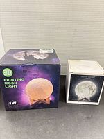 Front view of both boxed moon lamps showing sizes