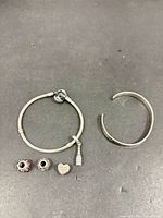 Full lot showing Pandora bracelet with attached charm, four loose Pandora charms, and hammered cuff bangle
