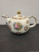 Right side view of teapot showing floral pattern and gold trim