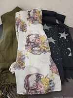 Group shot of three scarves: olive, skull print, star print