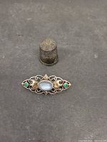 Front view of thimble and brooch