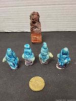 Group shot of soapstone chop, four turquoise figurines, coin for scale