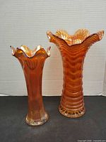 Two marigold carnival glass vases, swung and ripple styles, side by side