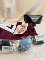 Dog jersey, two packaged sunglasses, black sunglasses case displayed together