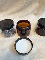 Three amber plastic jars, one open showing interior and foam seal