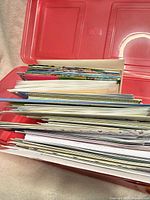 Side view of stacked greeting cards inside red plastic box