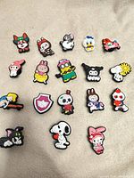 Group shot of 18 assorted rubber shoe charms laid out on fabric