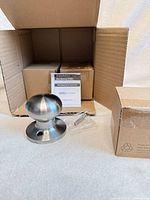 Single brushed nickel dummy knob, screws, instructions, open box visible