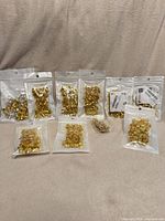 Multiple clear bags filled with gold and silver braid cuffs displayed on a surface