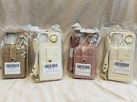 Four packaged faux leather phone wallet cases in beige, ivory, rose, ivory with straps